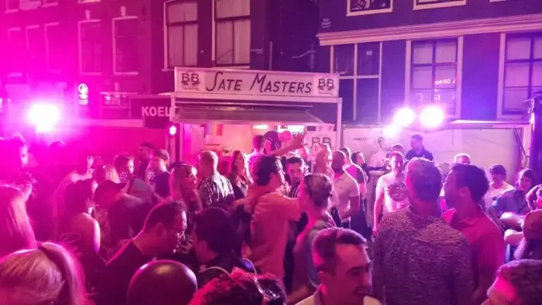 Feestende mensen in Amsterdam met Sate Masters B&B op achtergrond